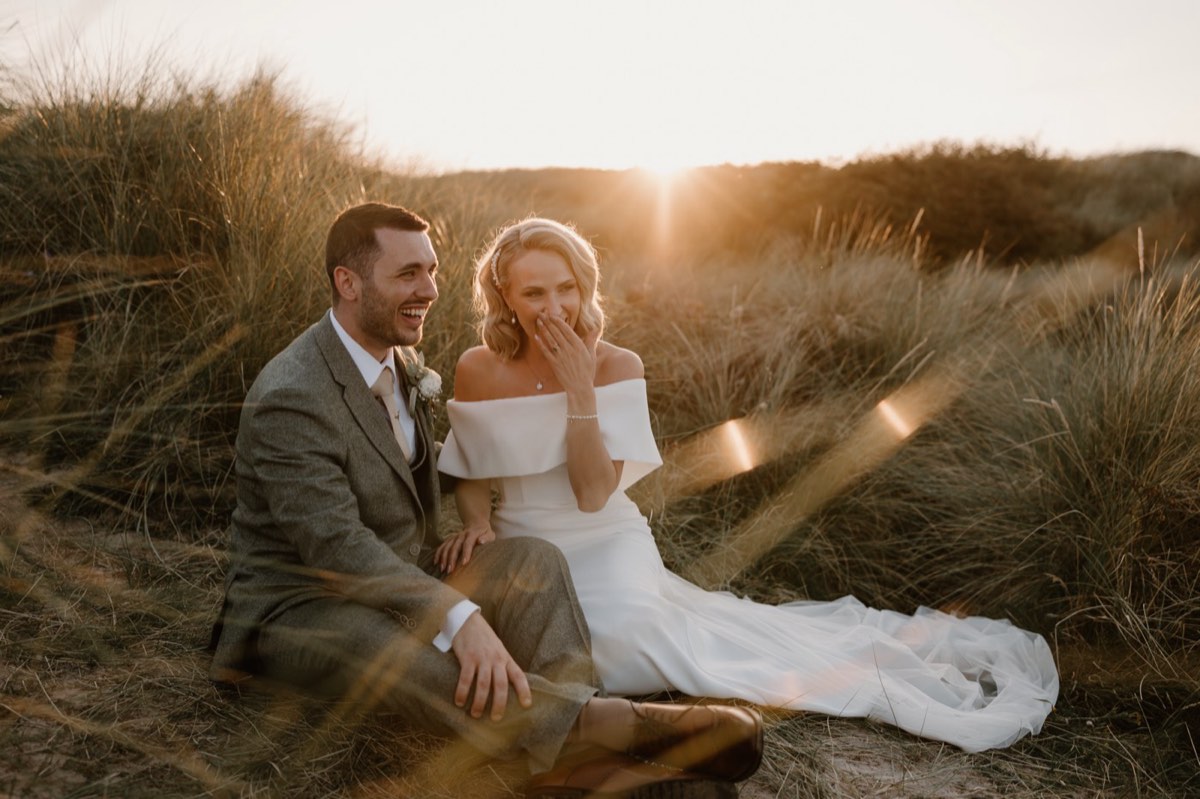 A couple sitting in the dunes at Newton Hall at sunset